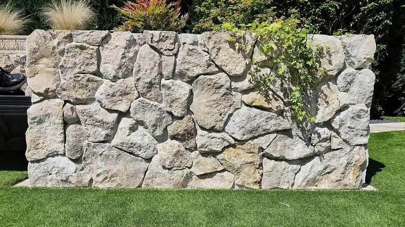 Gartenmauer aus Travertinsteinen mit Bepflanzung